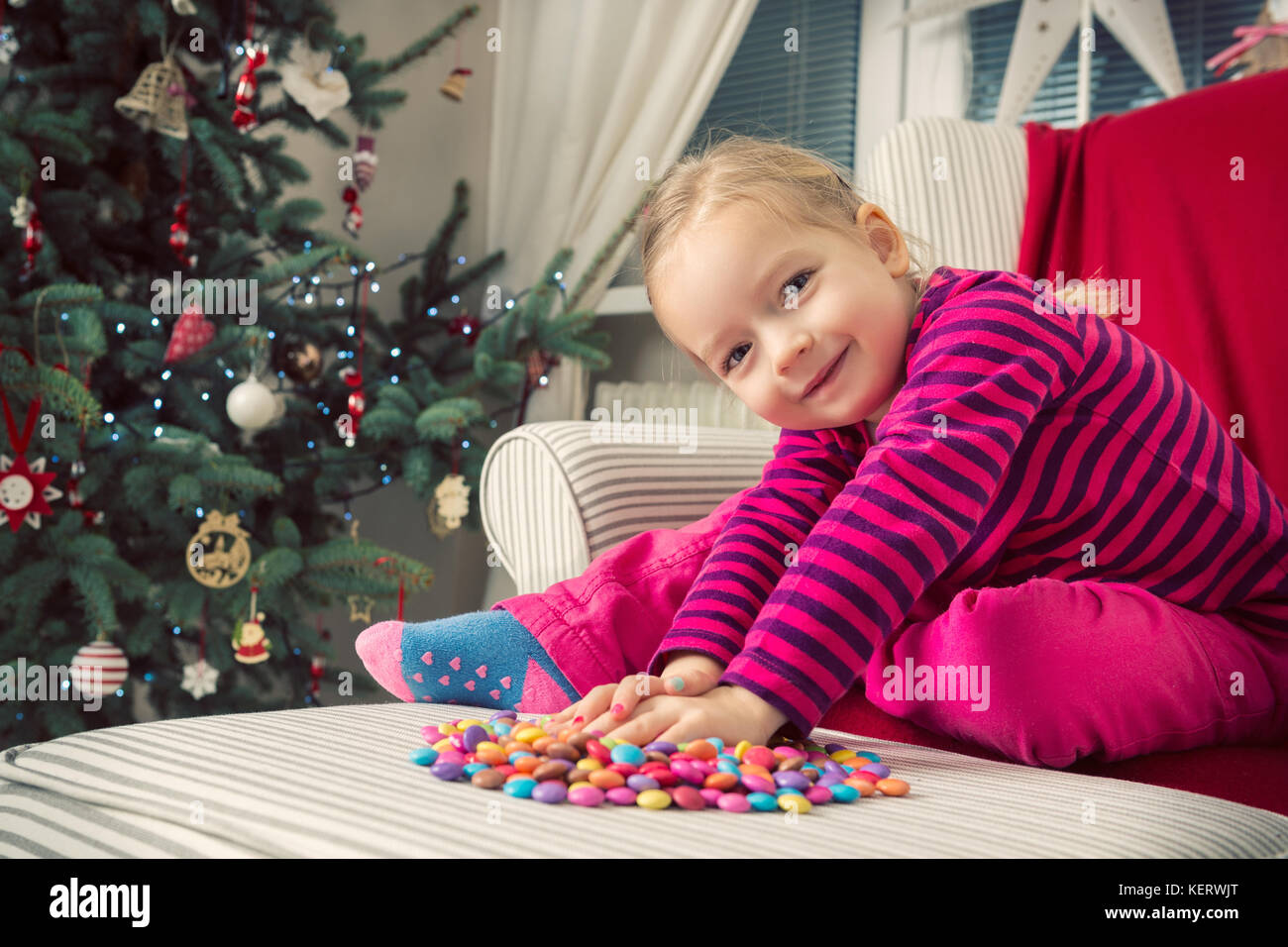 Adorable preschool girl playing with sweets on xmas eve Stock Photo