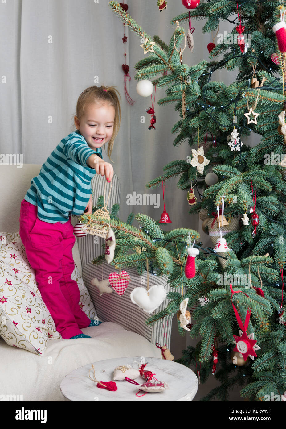 Child helping to decorate xmas tree Stock Photo