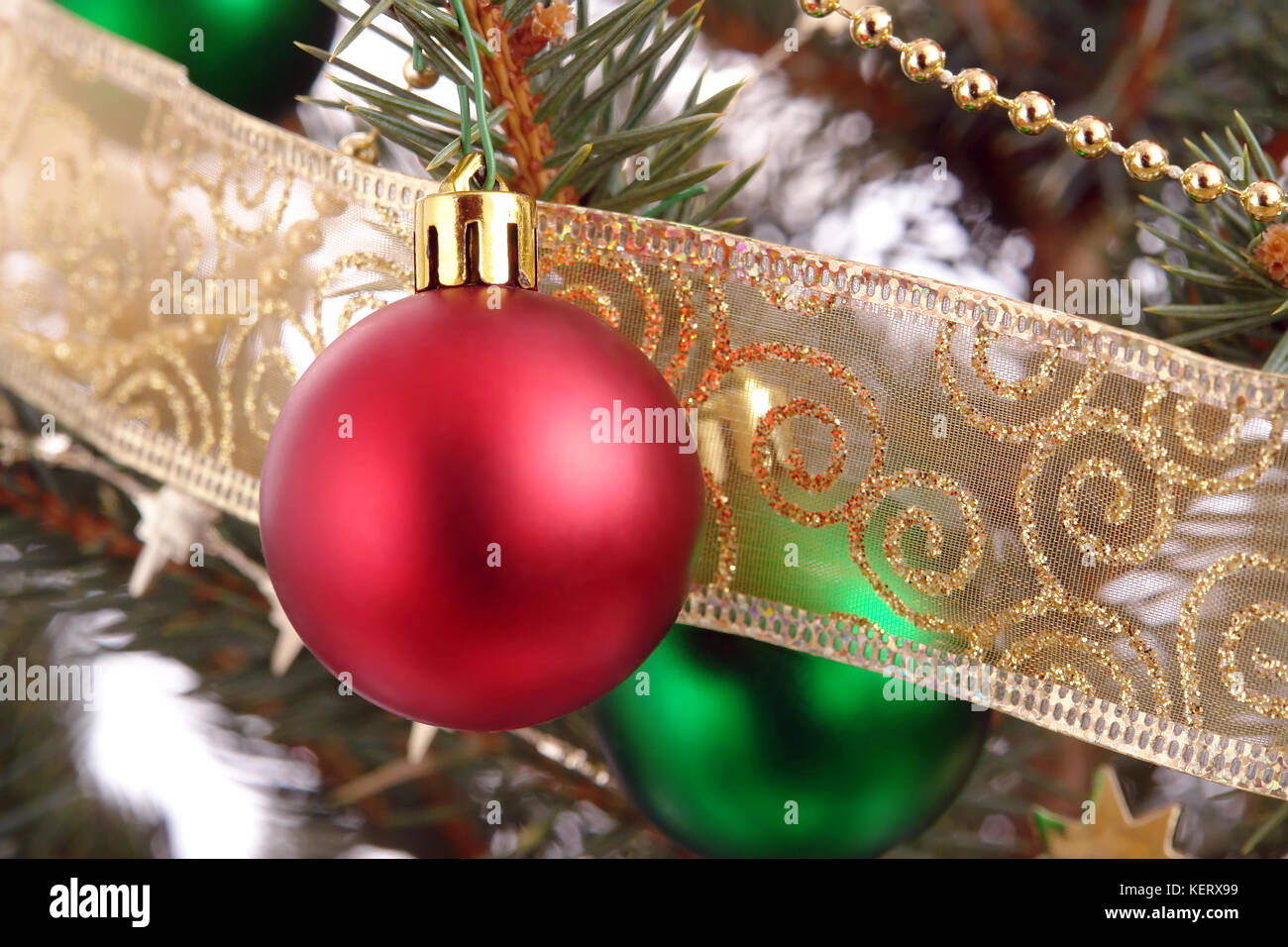 Red christmas ball with golden ornaments hanging on spruce branch Stock Photo