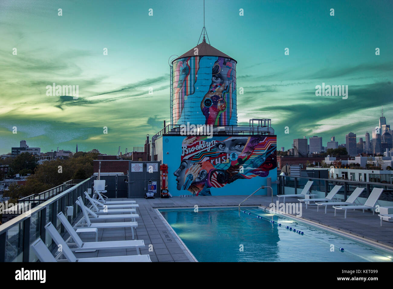 An old water tank and swimming pool on the roof of a luxury Brooklyn apartment building at sunset. Stock Photo
