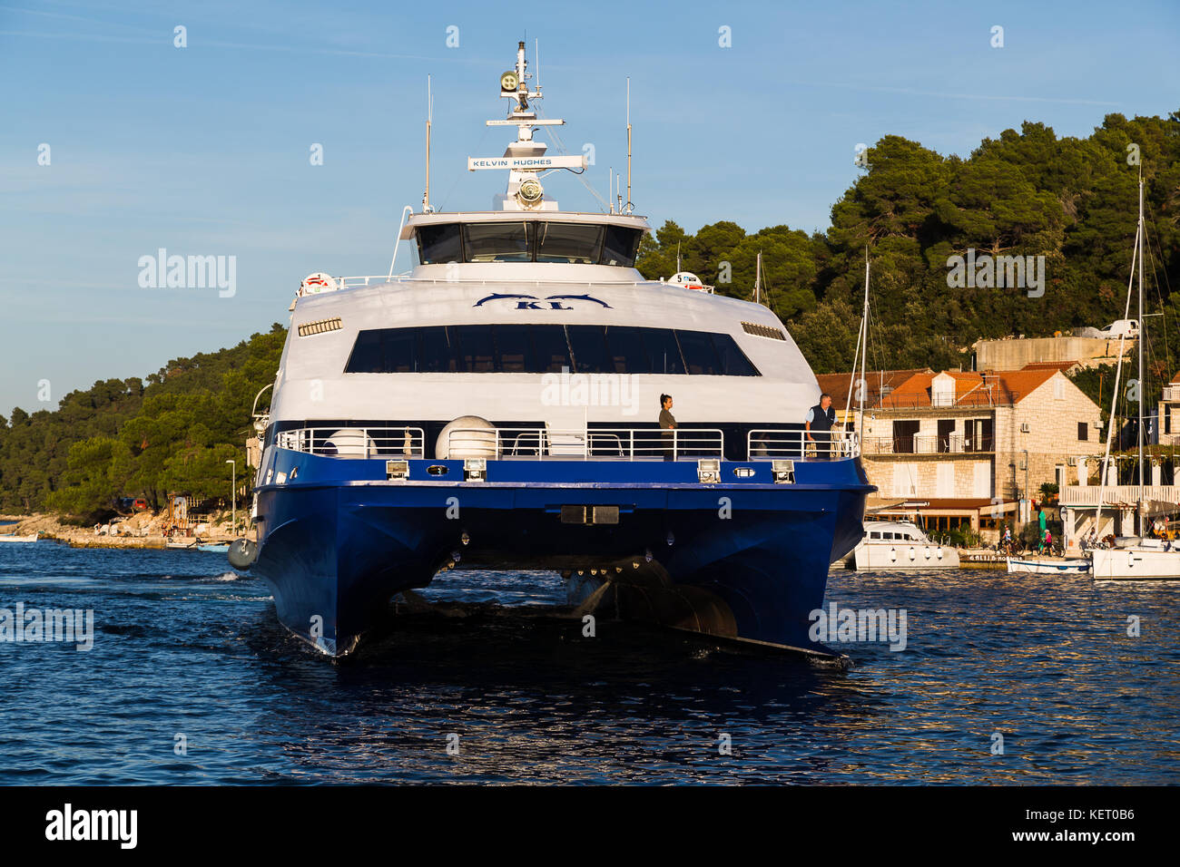 A Large Passenger Ferry catamaran Slowly Approaches The Lush Green a-large-passenger-ferry-catamaran-slowly-approaches-the-lush-green
