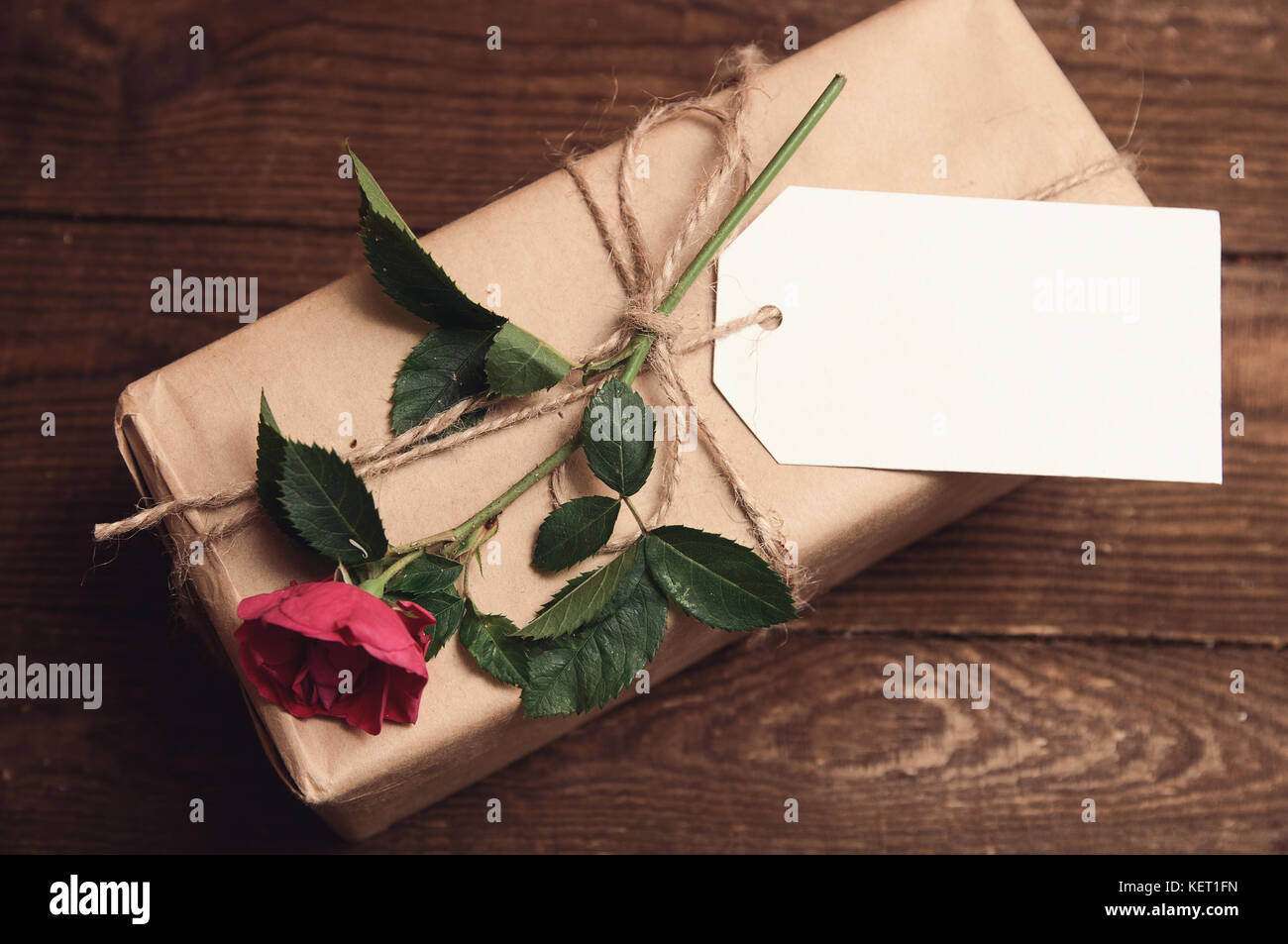 gift wrapped in kraft paper with rose flower on top Stock Photo