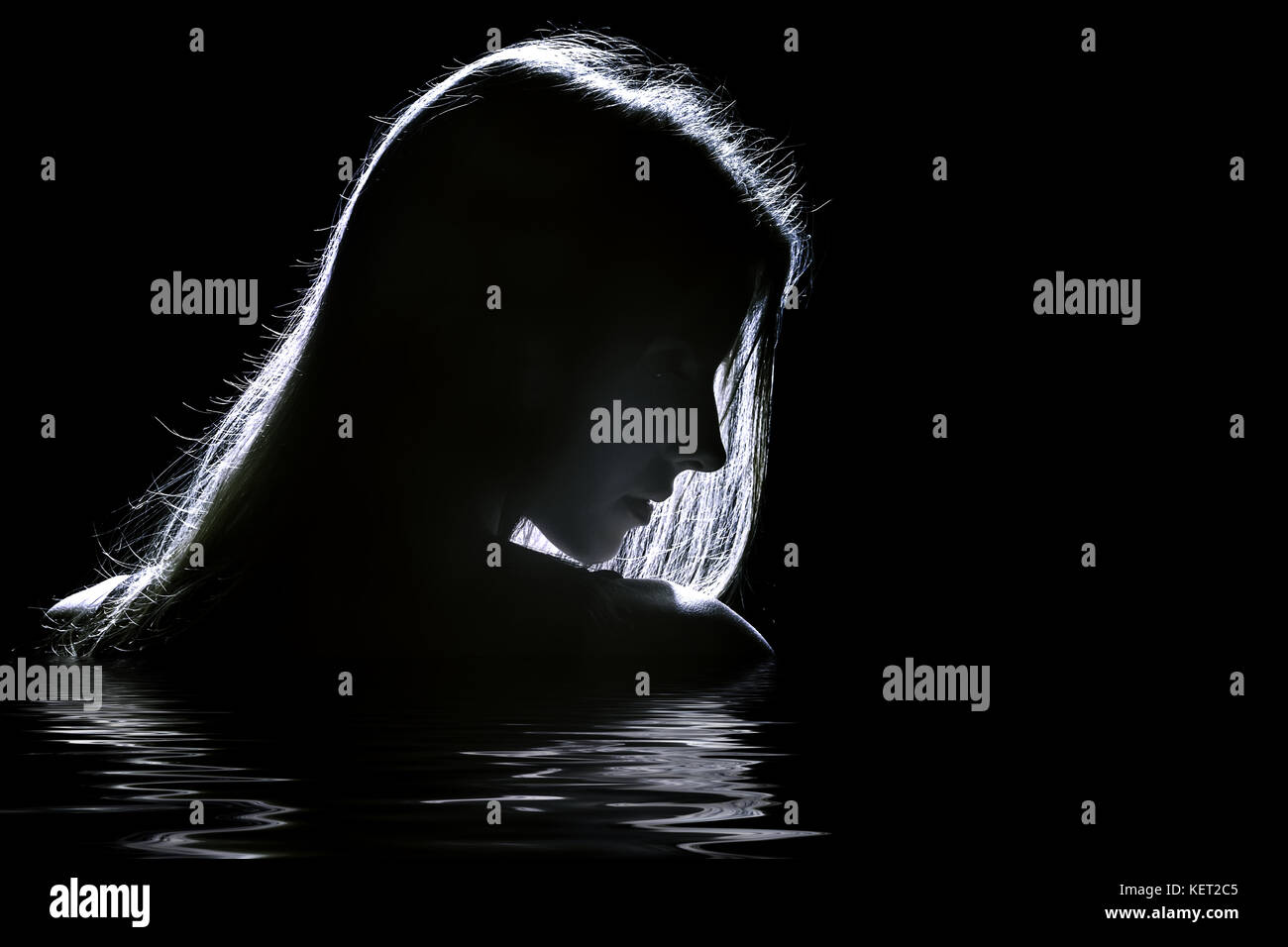 sad woman profile silhouette in dark with reflection on water Stock Photo