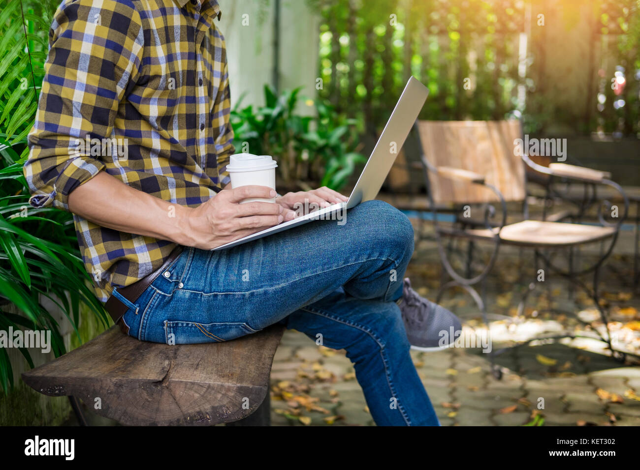man on week-end working on laptop computer outdoor in a park garden ...