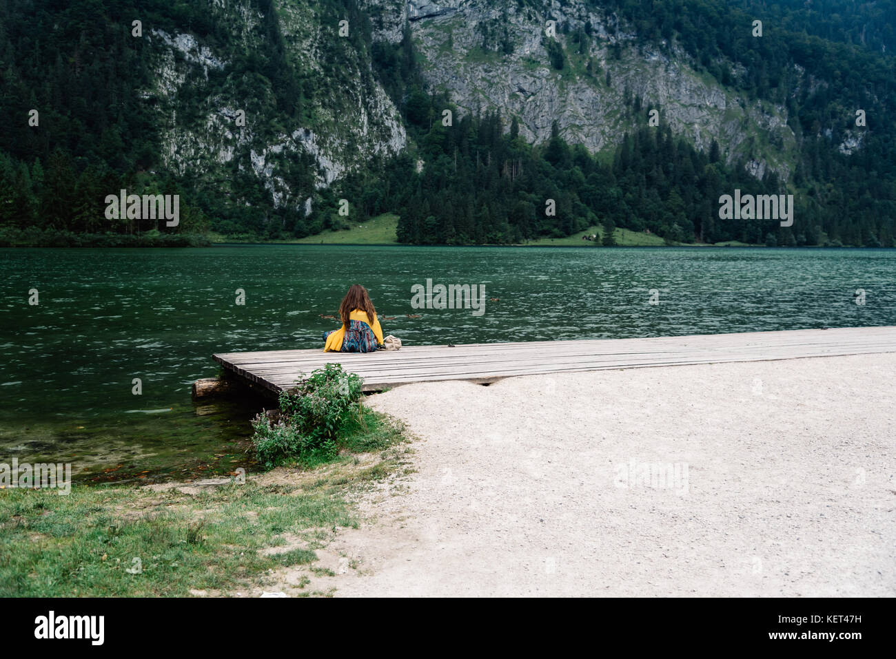 Girl sitting on the pier looking at beautiful lake Stock Photo - Alamy
