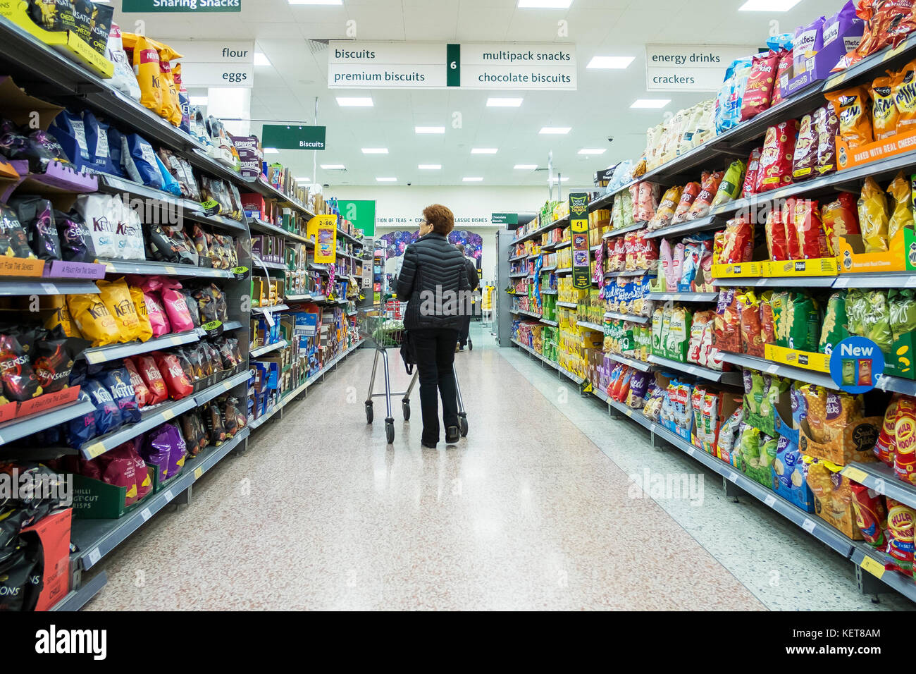 Shopping in a Morrisons supermarket shopper walking down an aisle in