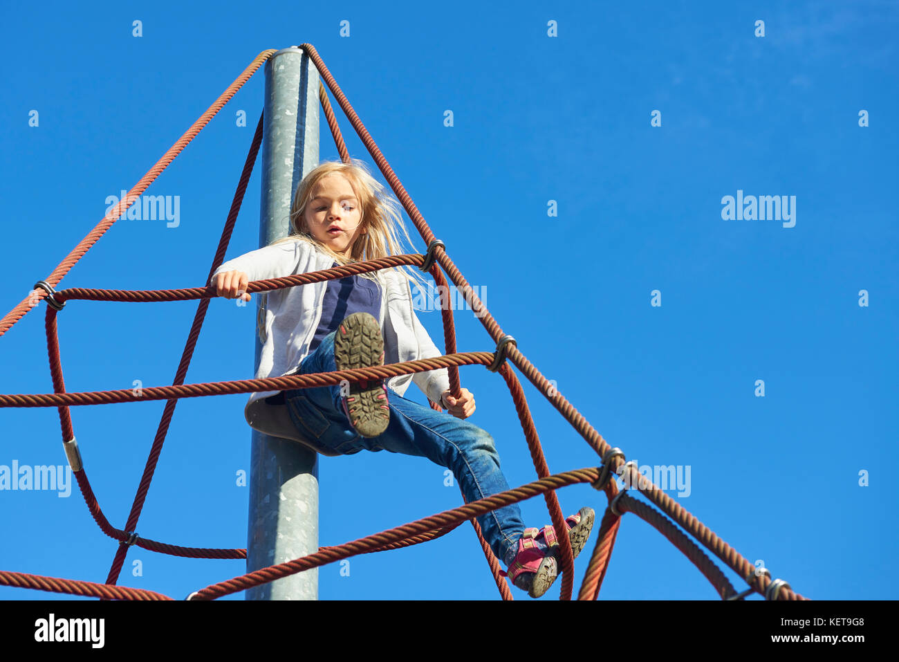 Active young child girl climbing the spider web playground activity. Children outdoor activities. Stock Photo