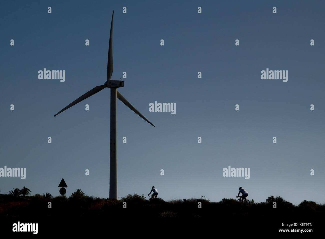 Cyclists riding near a wind turbine Stock Photo