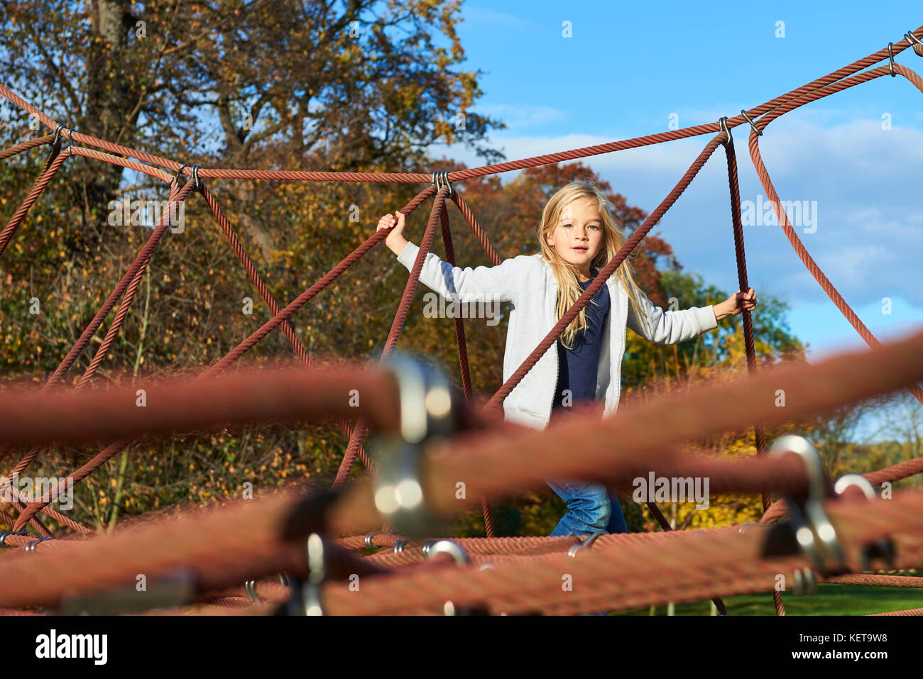 Active young child girl climbing the spider web playground activity. Children outdoor activities. Stock Photo