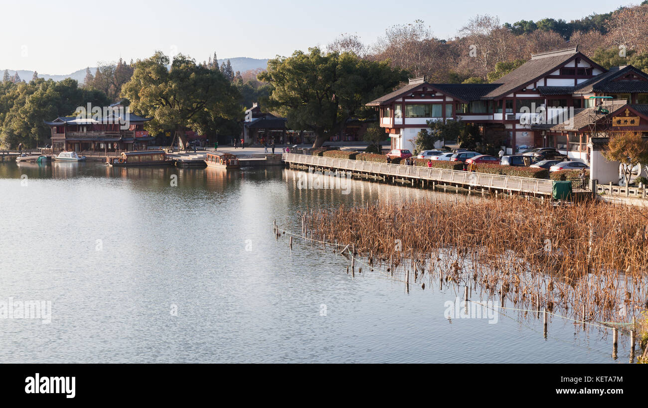 Hangzhou, China - December 5, 2014: West Lake landscape, famous park in Hangzhou city. Ordinary people walk along the coast Stock Photo