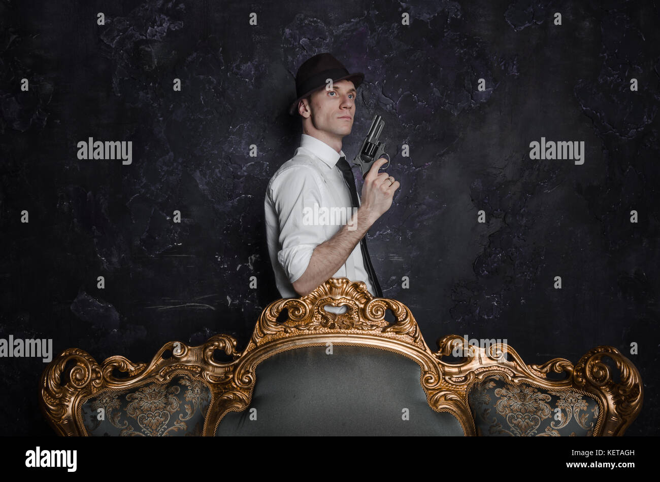 Handsome detective in hat holding a gun in the dark Stock Photo