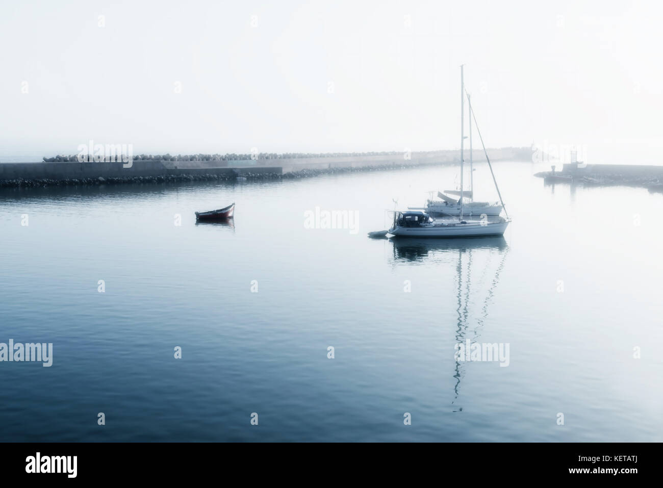 Two sailing boats (yachts) and a small motor boat anchored early morning. High key image with soft focus and glow. Stock Photo