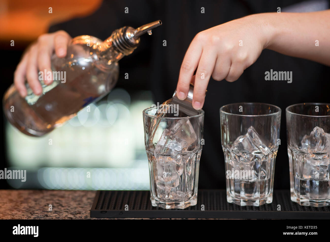 A bartender /  bar worker pours shots of spirits in a bar pub. Stock Photo