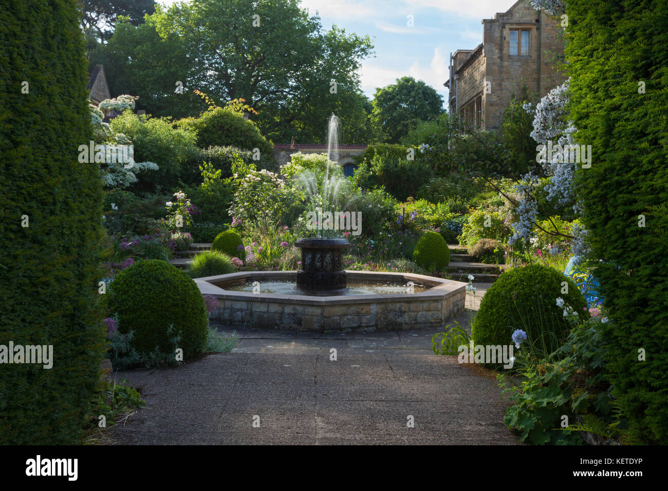 The White Sunk Garden and ornamental fountain backlit by early morning sunlight at Kiftsgate Court, Cotswolds, Gloucestershire, England. Stock Photo