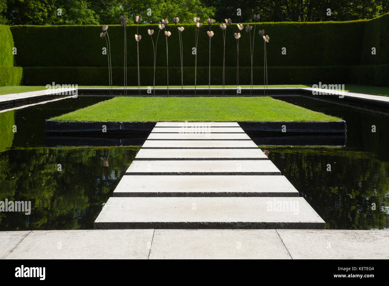 The contemporary Water Garden with modern art sculpture is enclosed by high yew hedges, Kiftsgate Court gardens, Cotswolds, Gloucestershire, England. Stock Photo