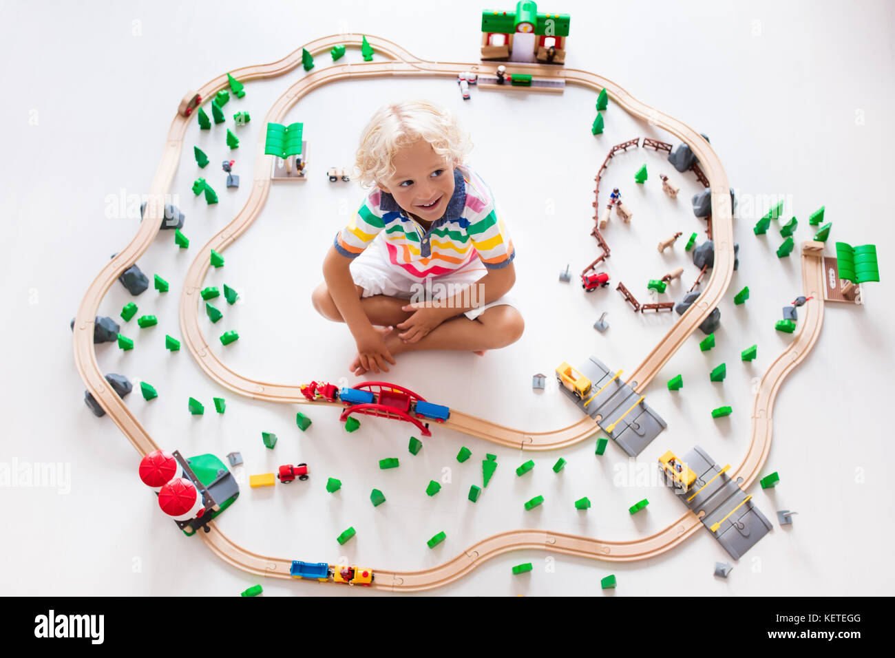 Kids play with toy train railway. Child playing with wooden trains
