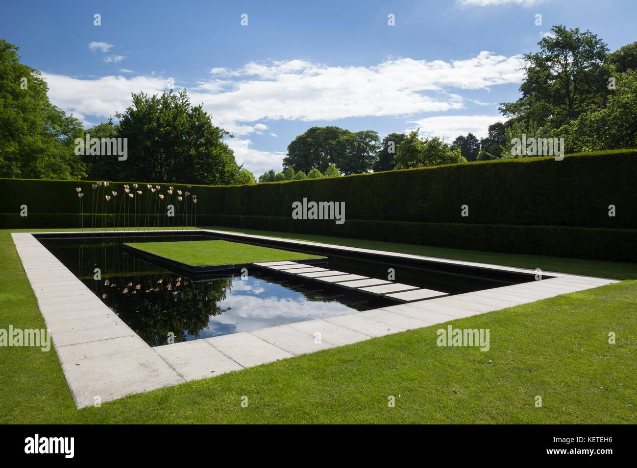 The contemporary Water Garden with modern art sculpture is enclosed by high yew hedges, Kiftsgate Court gardens, Cotswolds, Gloucestershire, England. Stock Photo