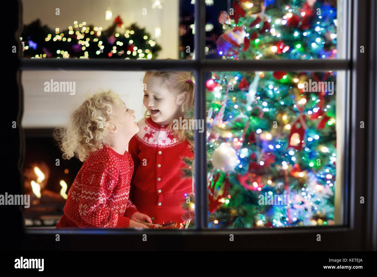 Children At Christmas Tree And Fireplace On Xmas Eve Family With