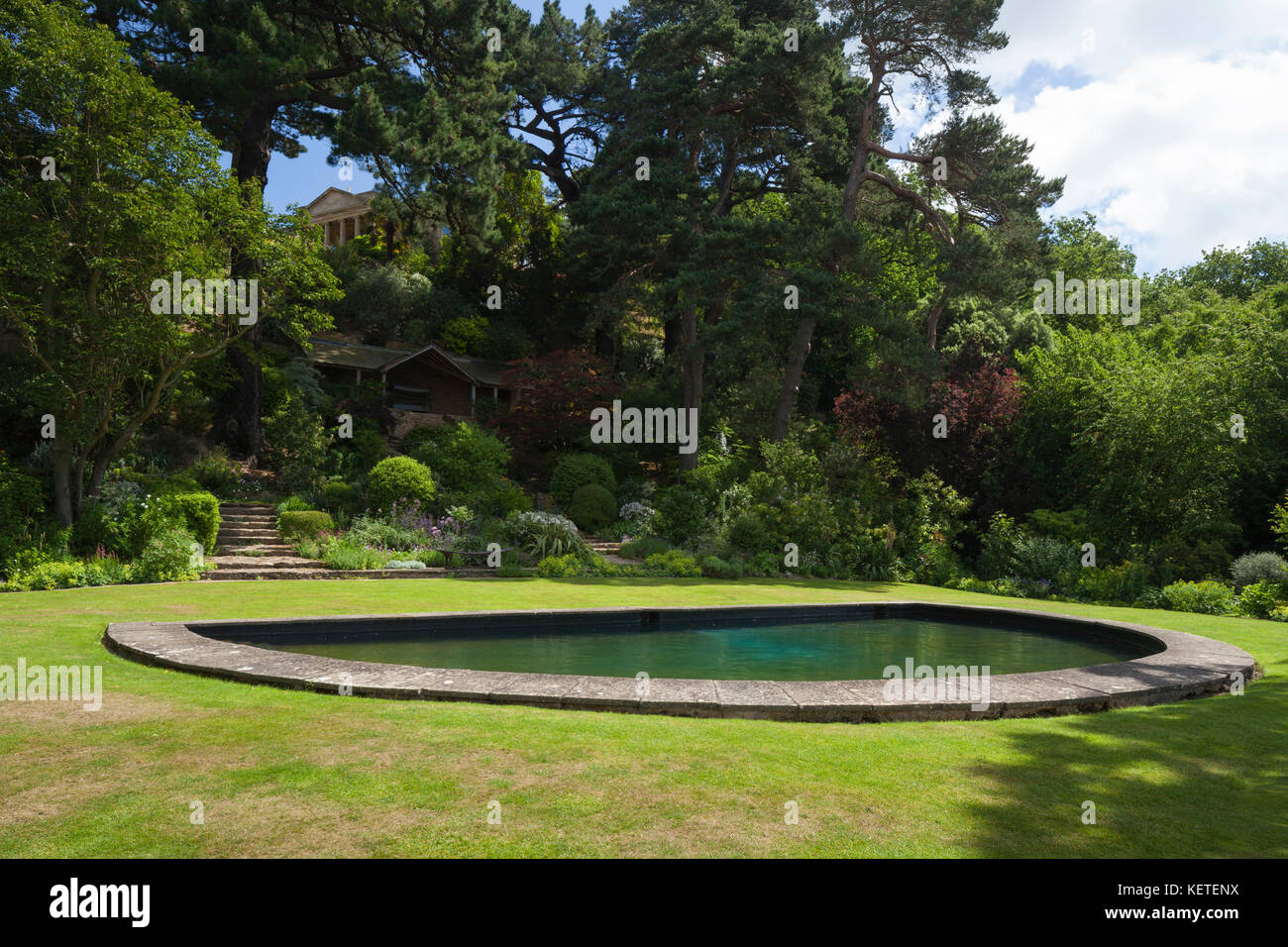 Beside the semi-circular bathing pool of the lower garden looking back towards the house of Kiftsgate Court, Cotswolds, Gloucestershire, England. Stock Photo