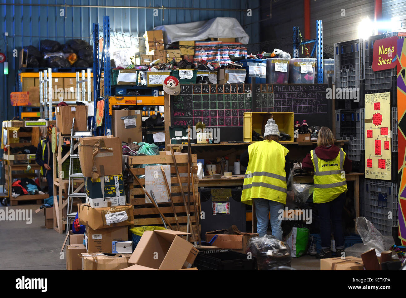 Volunteers sort donations at a warehouse in Calais where charities including Help Refugees and Care4Calais are providing food, clothing and personal hygiene items to migrants around the town, as one year on from the demolition of the camp dubbed "The Jungle" migrants continue to stay in Calais and attempt to cross the border to the UK. Stock Photo