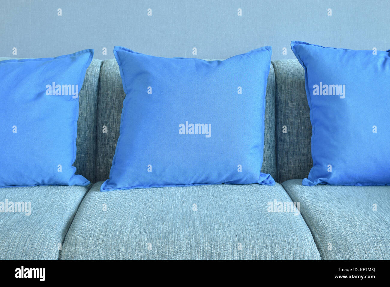 Blue pillows on light blue sofa with blue wall background Stock Photo