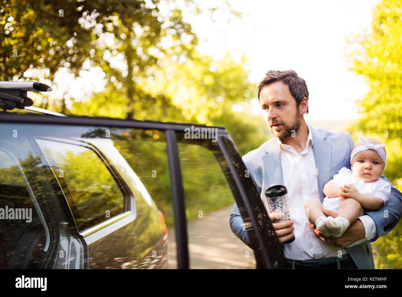 Man carrying his baby girl by the car. Stock Photo