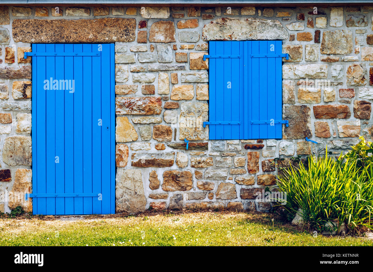 Vintage blue door and window on the facade of an old cottage stone wall ...
