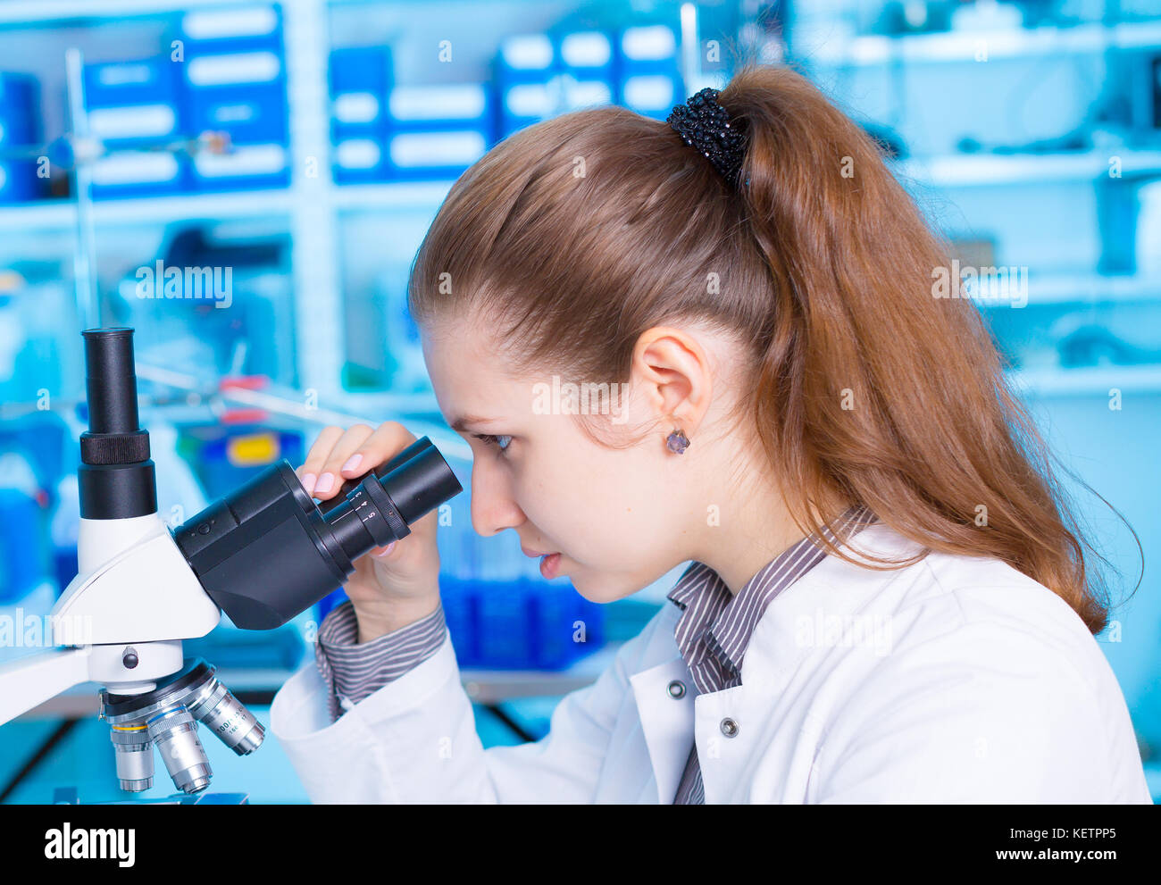 Young woman scientist looking a microscope in a laboratory. Girl