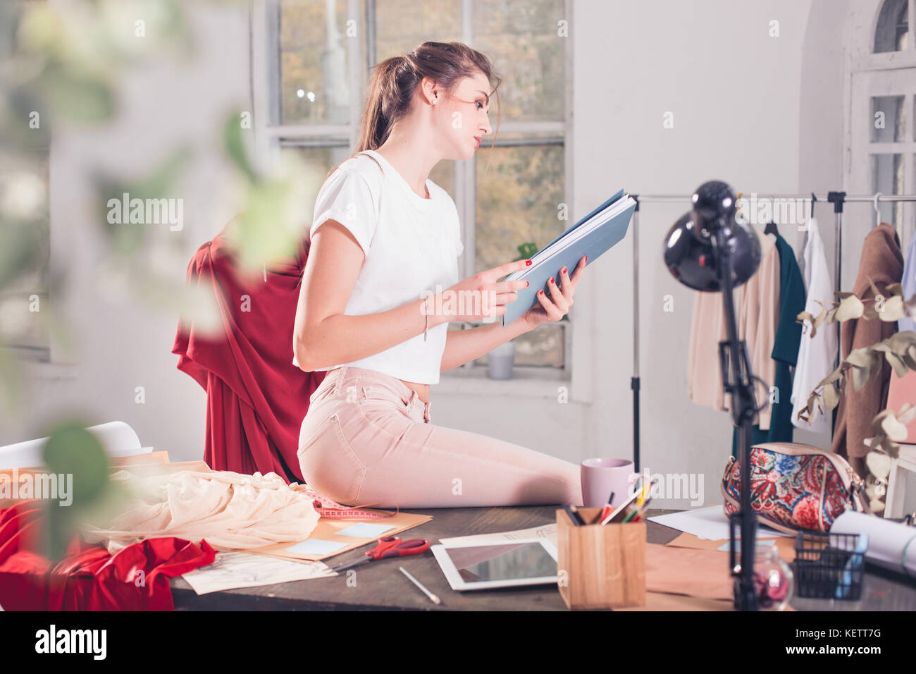 Fashion designers working in studio sitting on the desk Stock Photo - Alamy