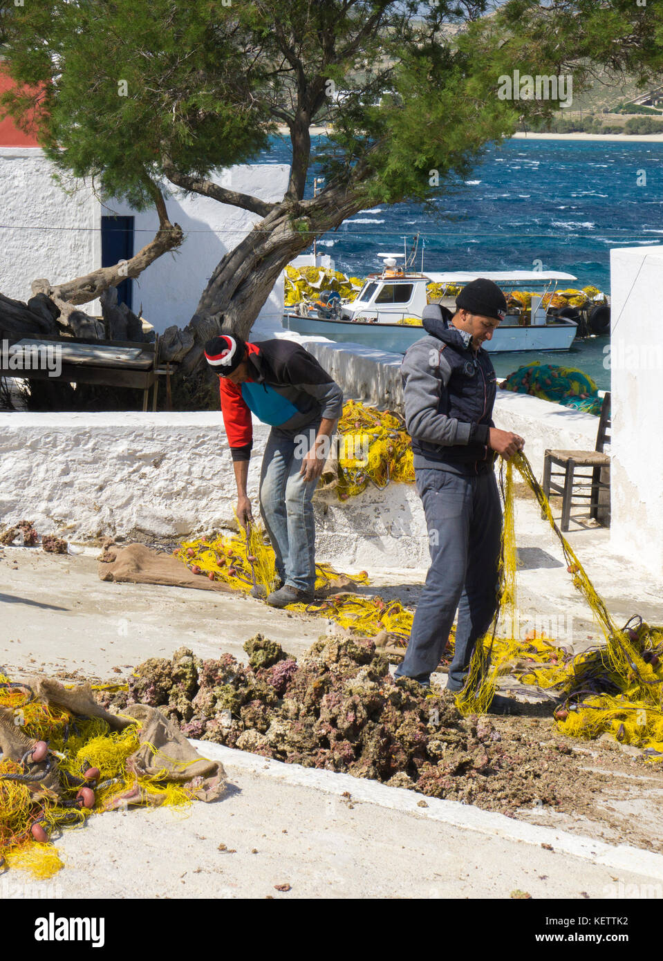 Fishermen repairing nets at Agia Anna Bay, Mykonos, Greece Stock Photo