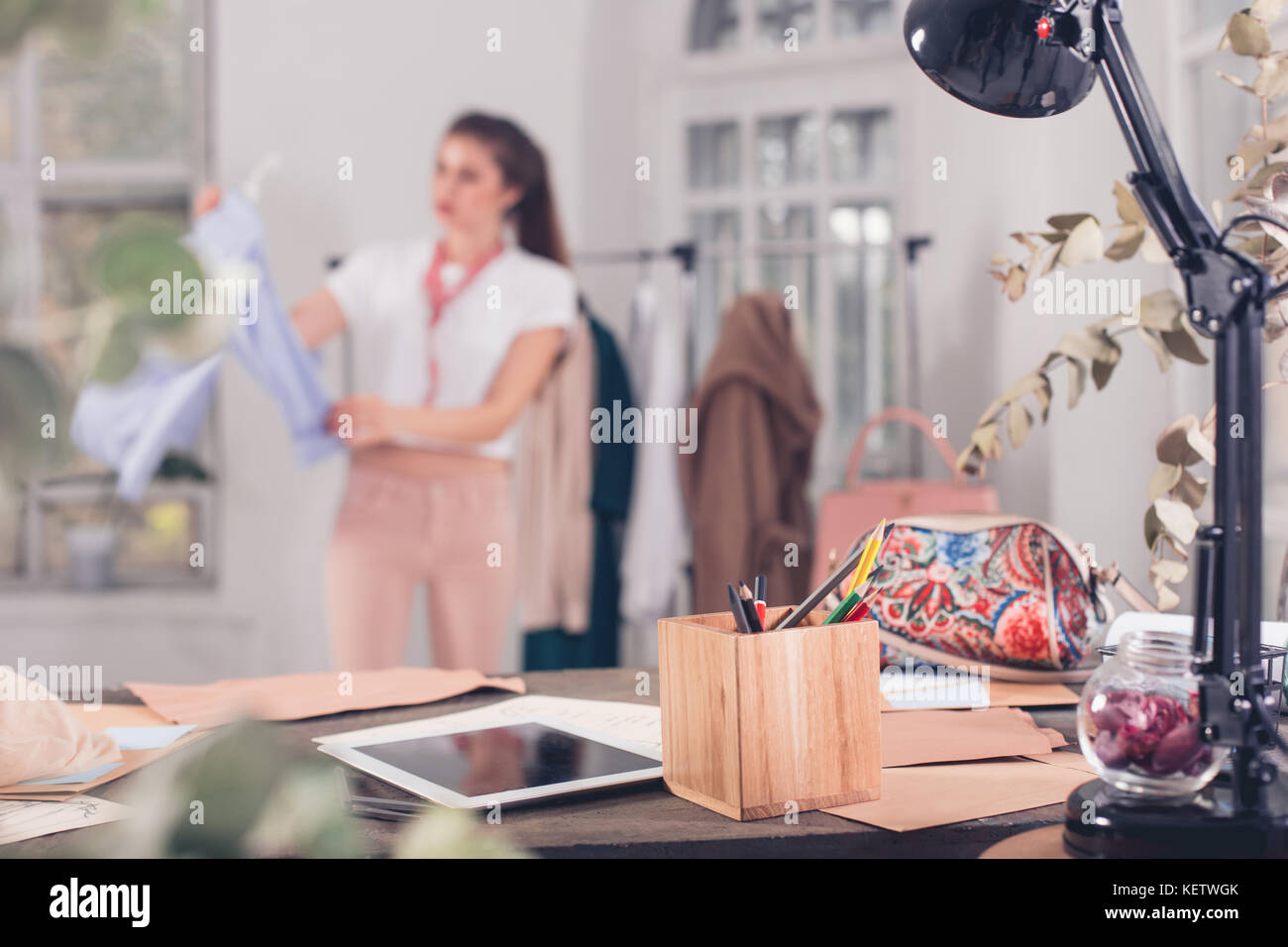 Fashion designers working in studio sitting on the desk Stock Photo - Alamy