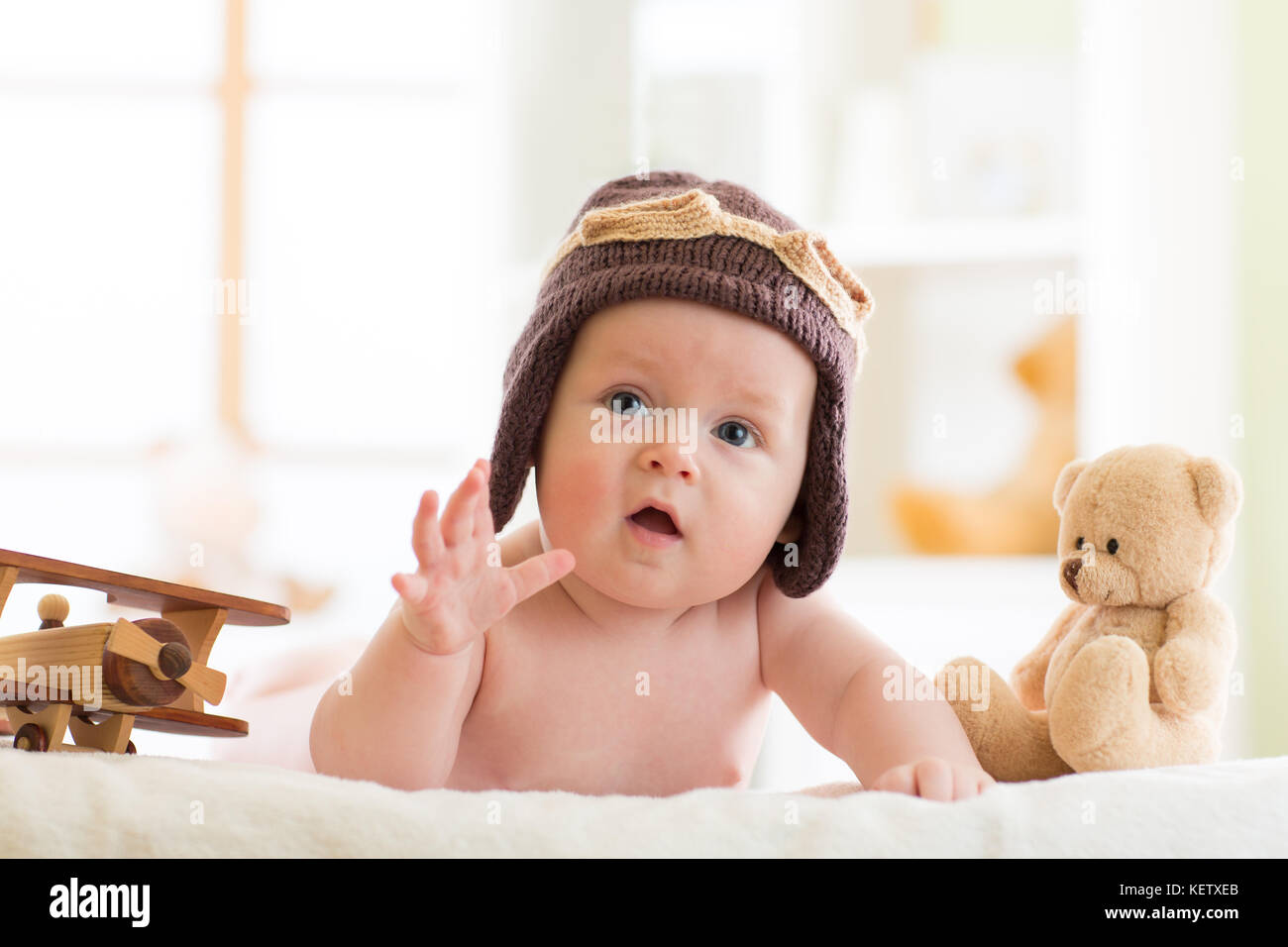 Funny baby boy weared pilot hat with wooden airplanes and teddy bear toys Stock Photo