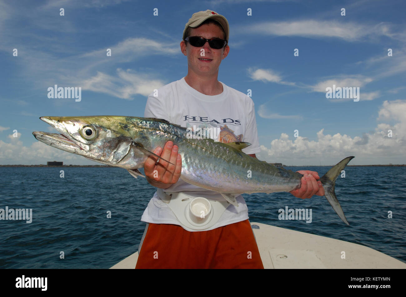 A young boy fisherman holds a kingfish or king mackerel caught while fishing offshore from Port Aransas, texas Stock Photo