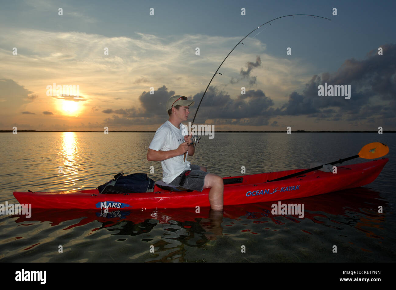 A young boy fishes from a kayak for redfish on the shallow flats near Port Aransas, texas Stock Photo