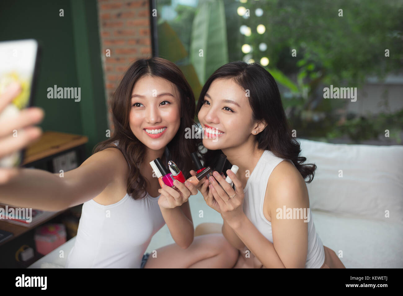 Two asian women in the bedroom on the bed  paint their nails and have fun Stock Photo