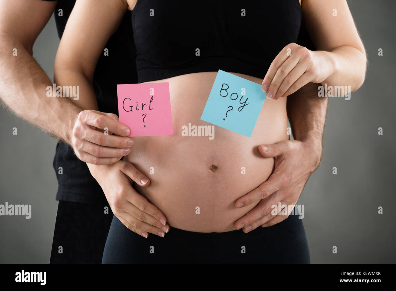 Mid Section Of Expecting Young Couple Holding Paper With Boy And Girl Text Stock Photo