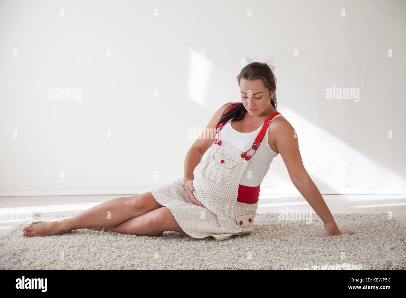 a pregnant woman sitting on the floor talking with a baby in the belly