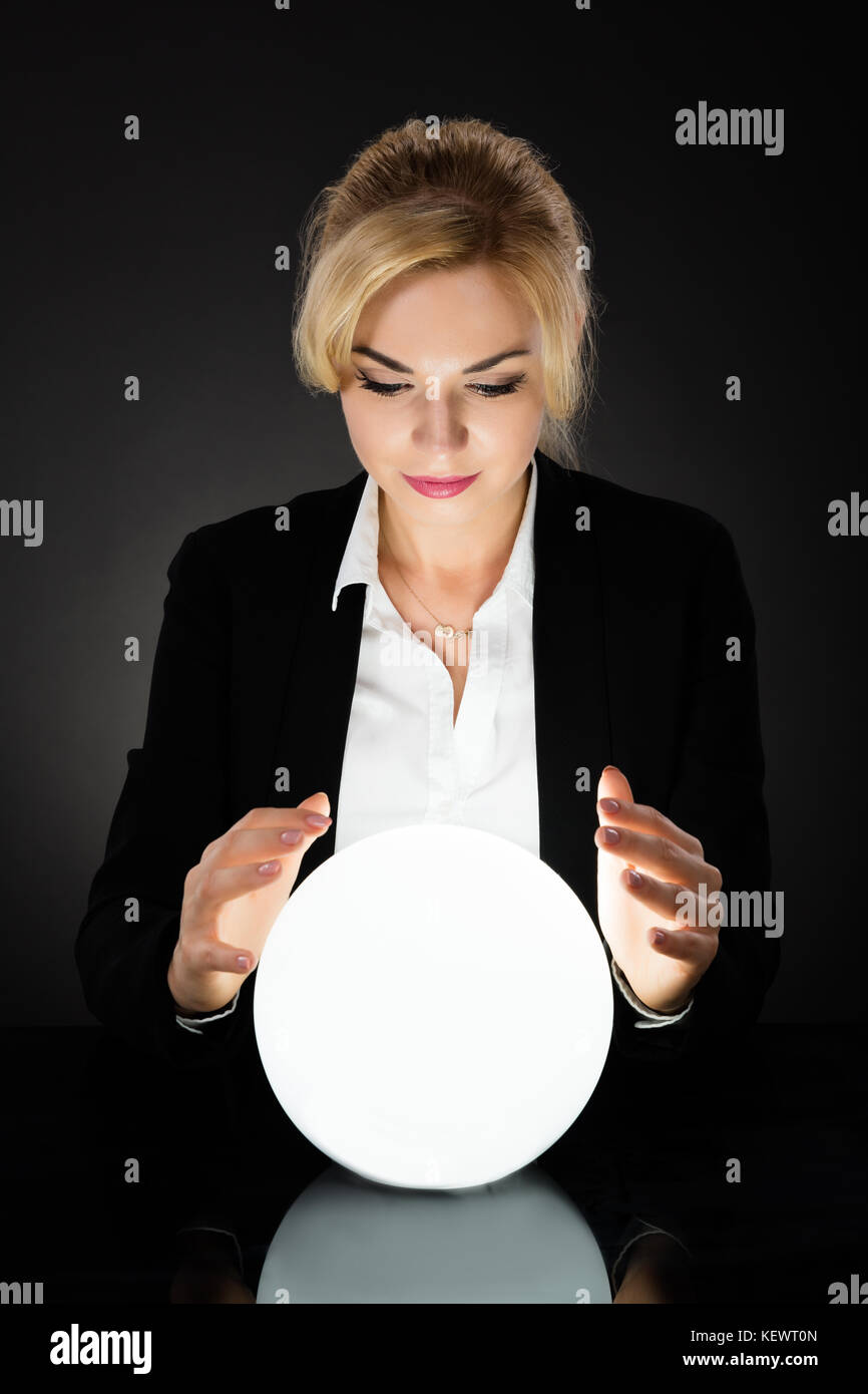 Young Businesswoman Looking Into The Future In A Crystal Ball On Black ...