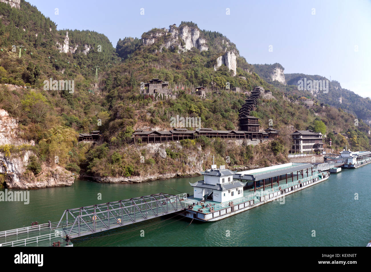 Extensive floating dockage to handle cruise passengers fronts a re-created traditional water village on the Yangtze River, a shore excursion for tourists cruising the river between Jingzhou and Chongqing. Visitors climb the covered stairway up to the village, a hefty hike. Stock Photo