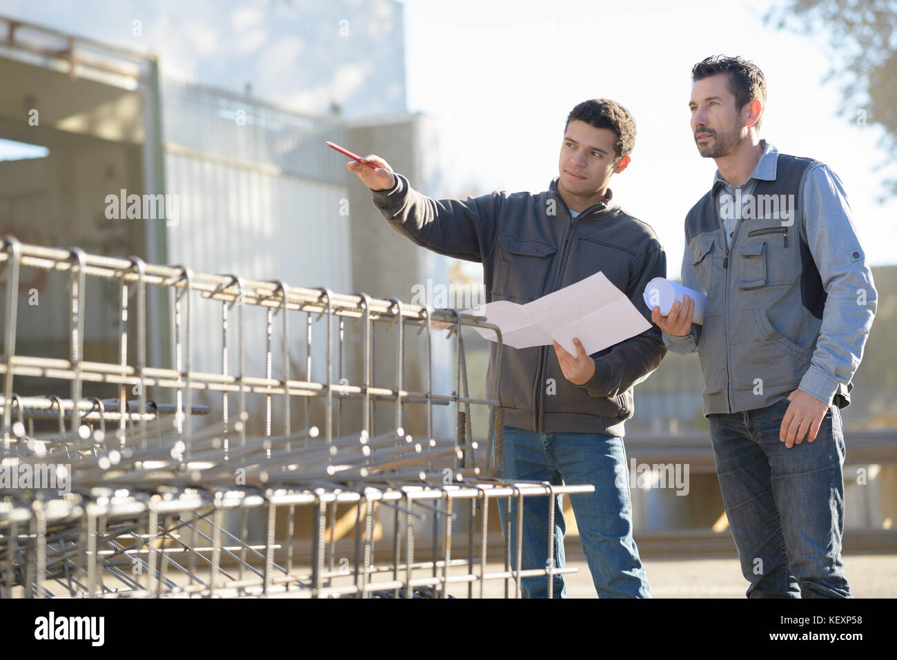 Men on construction site holding paperwork Stock Photo Alamy
