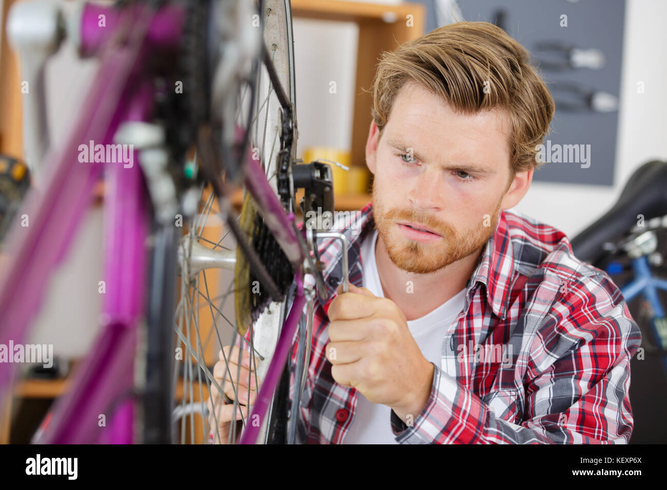 young man fixing bike wheel in store Stock Photo Alamy