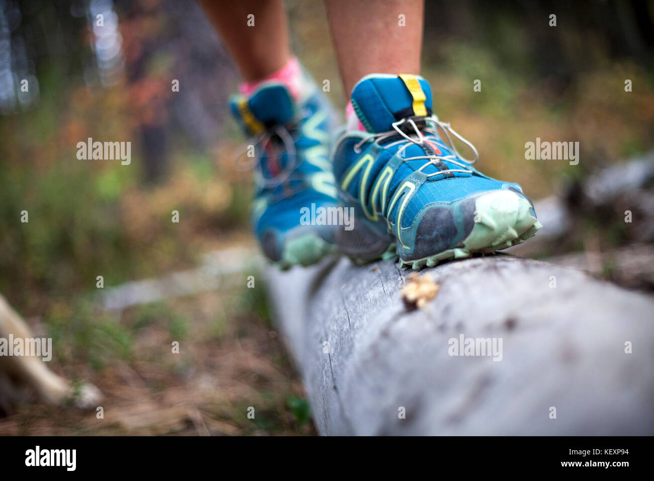 Photograph with running shoes on feet of woman balancing on log