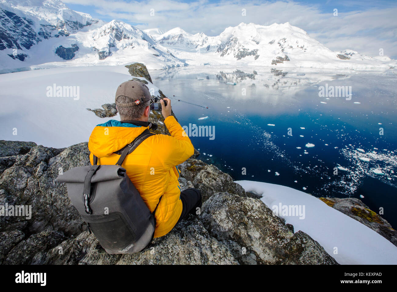 A passenger from an Antarctic cruise ship amongst stunning coastal scenery beneath Mount Walker in Paradise Bay off Graham Land on the Antarctic peninsula. The peninsula is one of the most rapidly warming places on the planet. Stock Photo