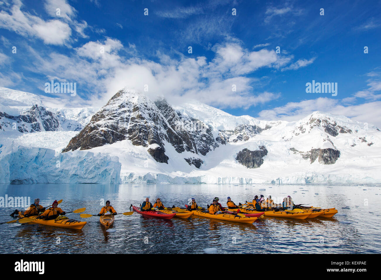 Members of an expedition cruise to Antarctica sea kayaking in Paradise Bay beneath Mount Walker on the Antarctic peninsula. The Antarctic peninsula is one of the most rapidly warming areas on the planet. Stock Photo