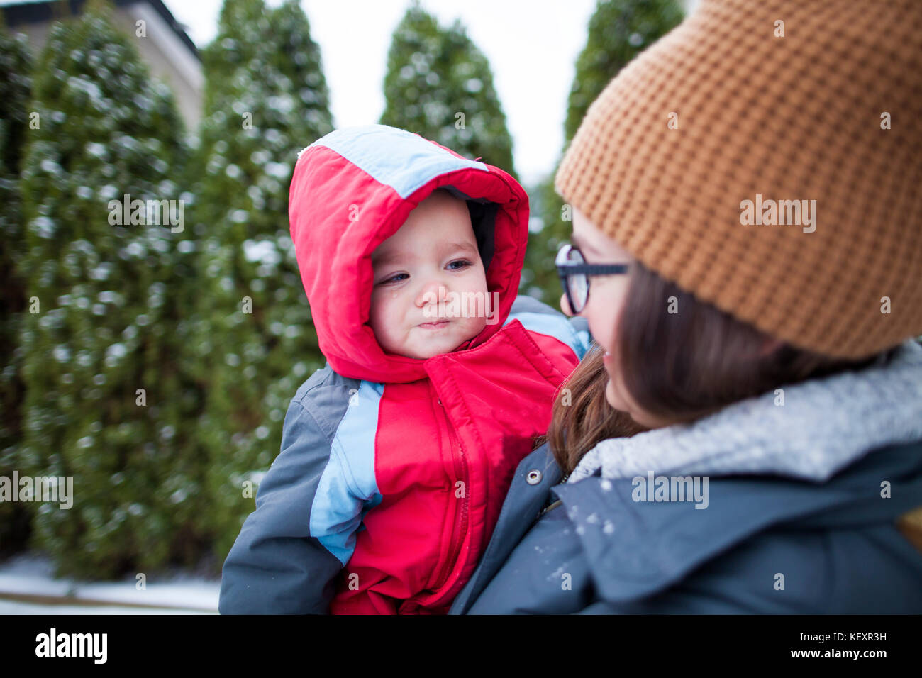 Mother holding baby outdoors in winter while wearing warm clothing, Langley, British Columbia, Canada Stock Photo