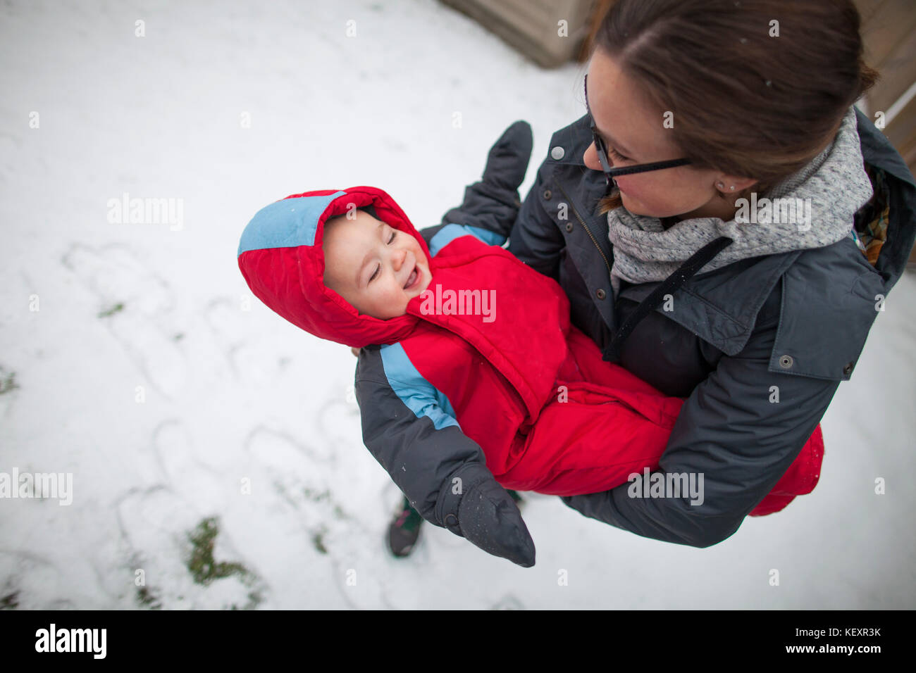 Mother holding laughing baby outdoors in winter while wearing warm clothing, Langley, British Columbia, Canada Stock Photo