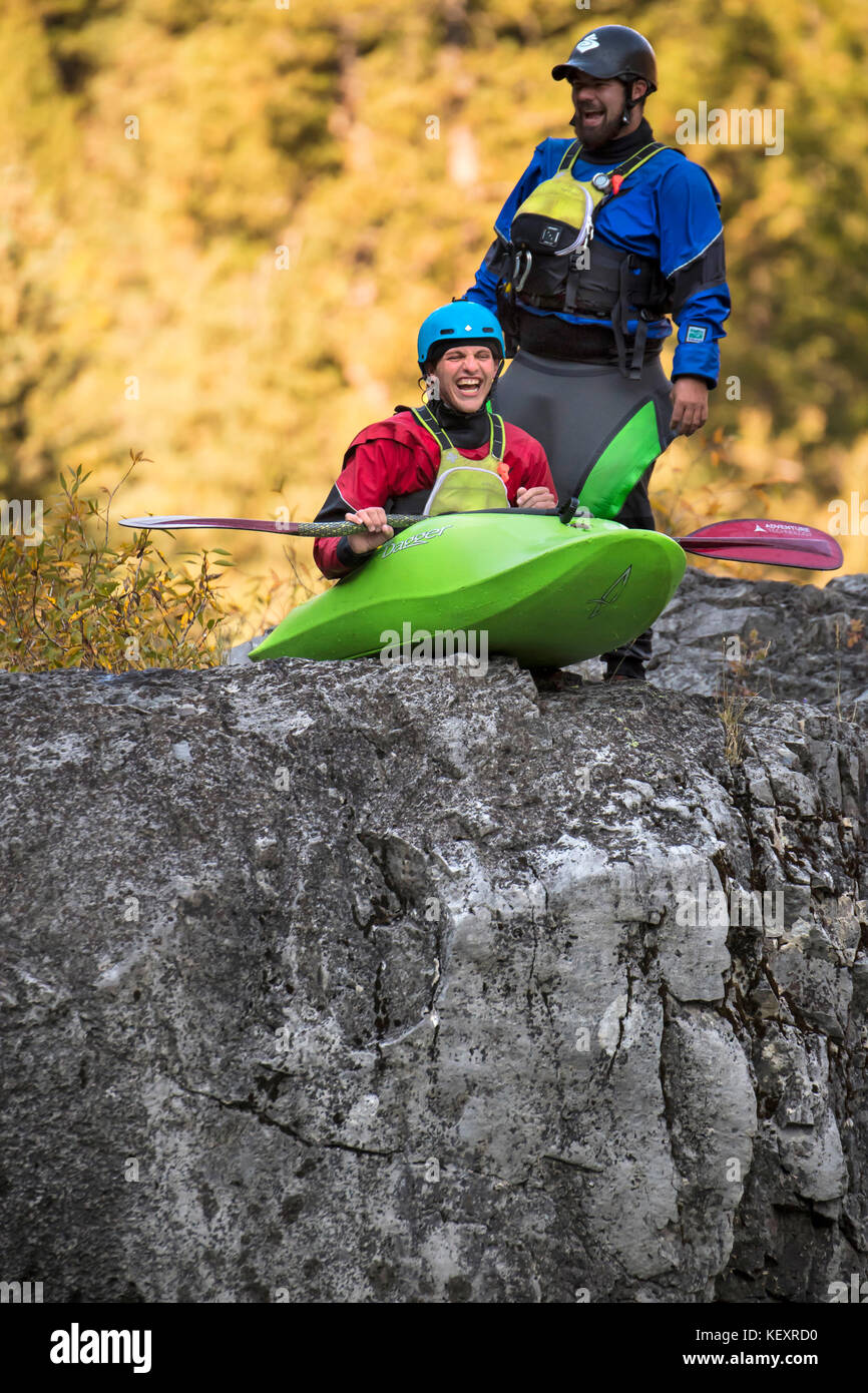Kayaker laughing while preparing to drop into river from top of rock, Jackson Hole, Wyoming, USA Stock Photo