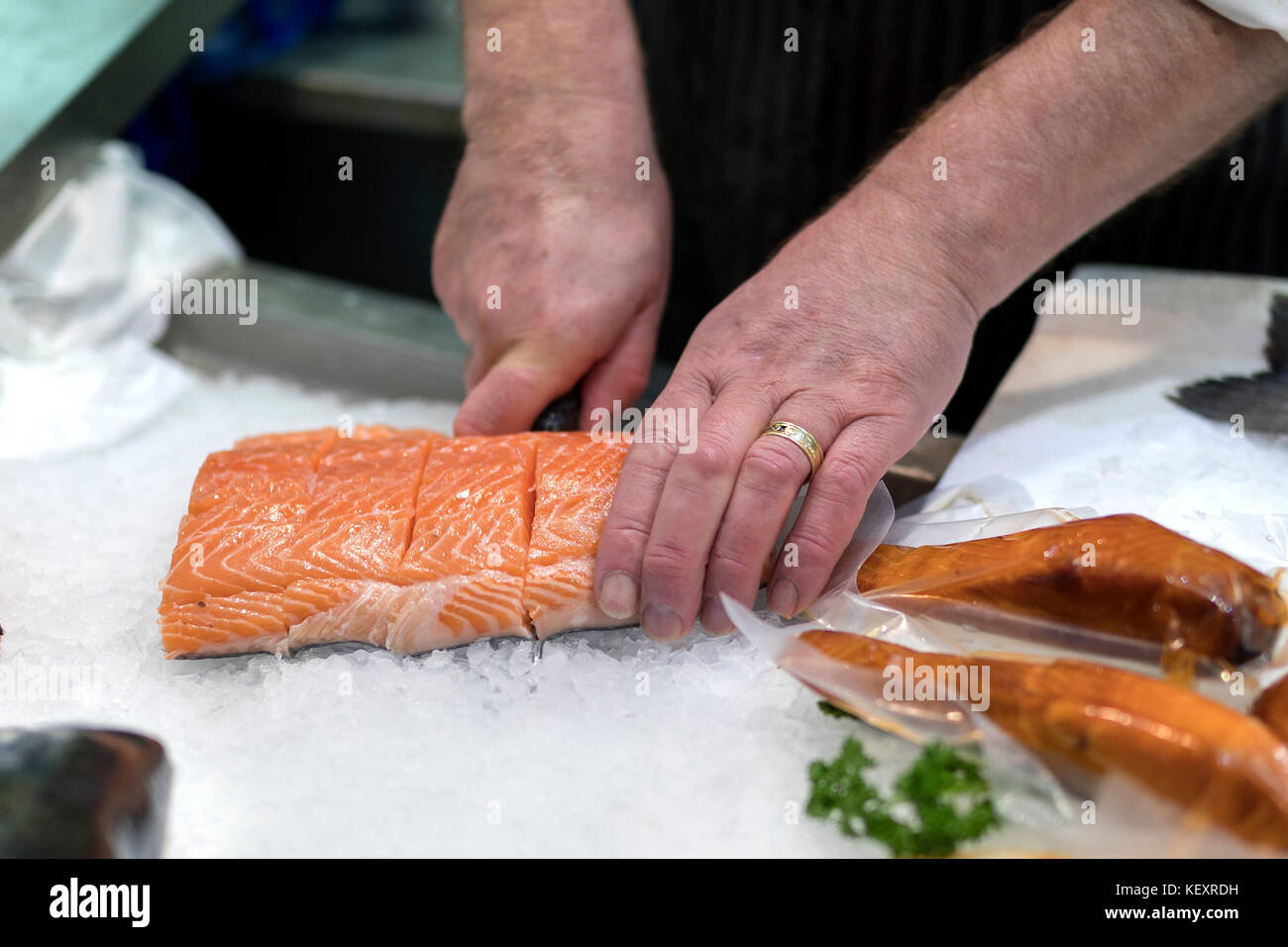 British fish monger slicing, filleting or cutting fresh slamon on ice on a market staff in Yorkshire, England Stock Photo