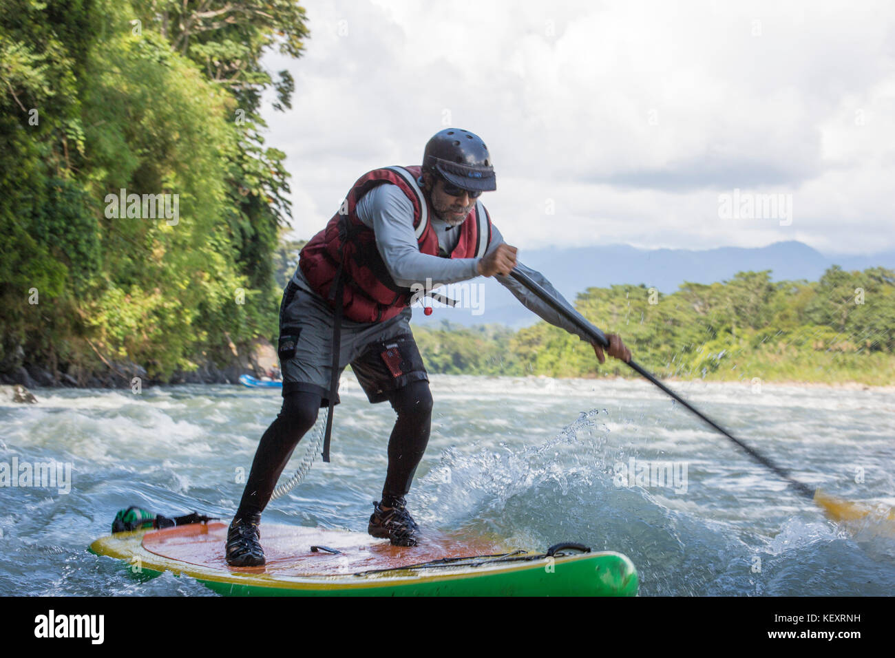 Man navigates whitewater on standup paddleboard while on Peru jungle river expedition Stock