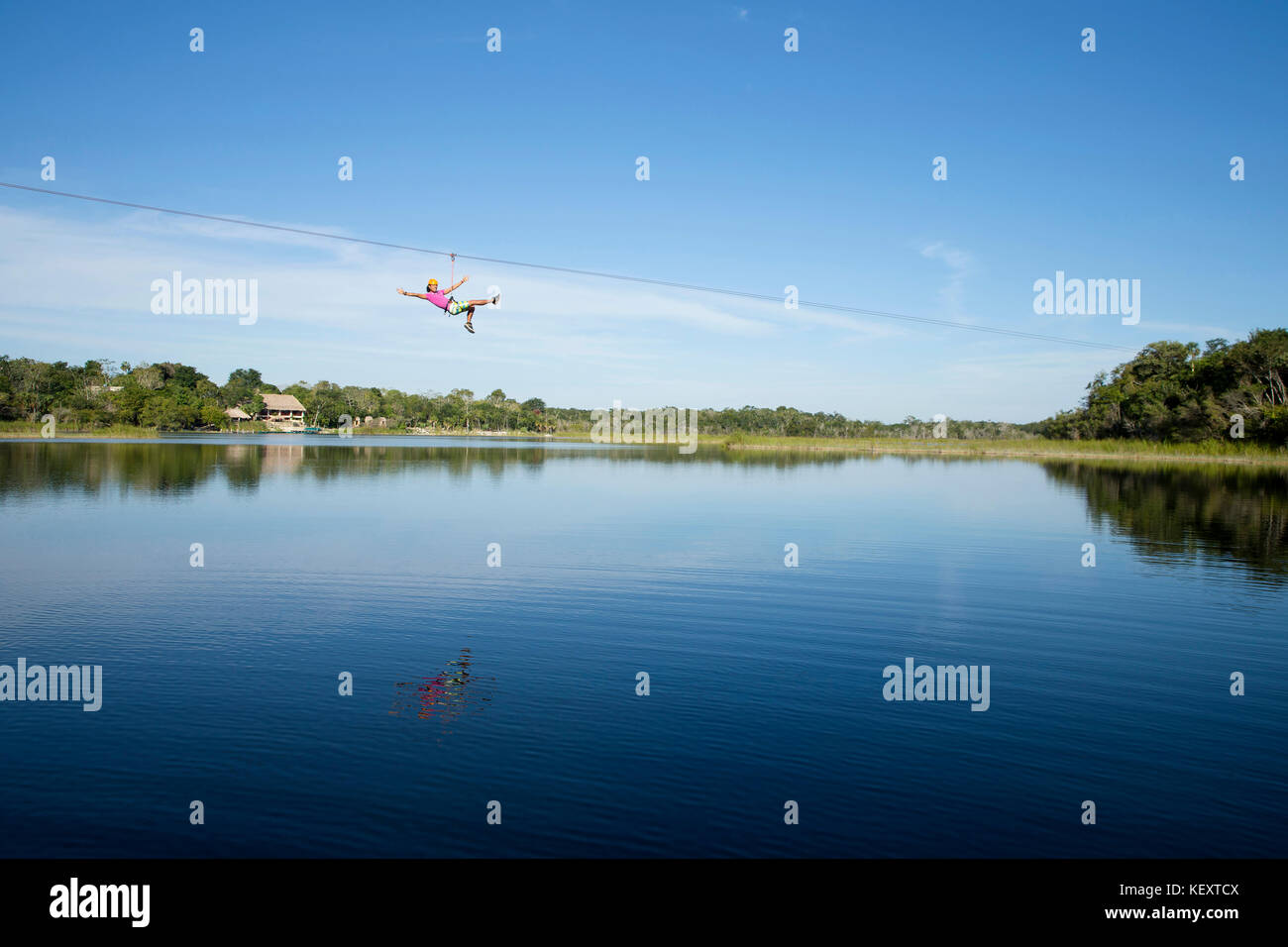Tourist enjoying zip line over lagoon and cenotes of village near Cob